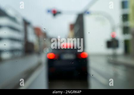 Traffic stand still on a cold wet day, shot through a windshield, focusing on the raindrops, lights out of focus. Stock Photo