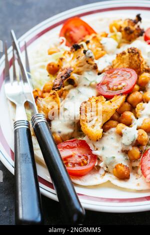 Open-faced vegetable burrito with flour tortillas, cabbage slaw, roasted cauliflower, roasted chickpeas and a spicy sauce. Stock Photo