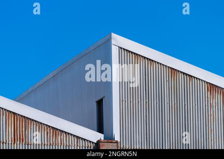 Metal corrugated iron factory wall and rooftop with a blue cloudless sky in Castlemaine Australia. Stock Photo