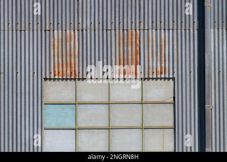 Metal background texture showing a corrugated iron factory wall and windows in Castlemaine Australia. Stock Photo