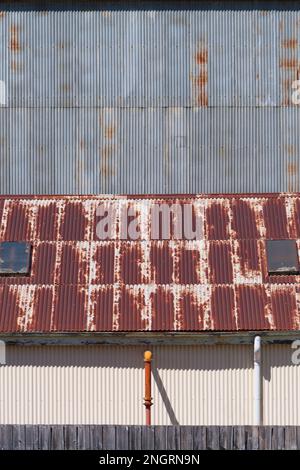 Background metal texture showing a corrugated iron factory wall, rusted roof and wall pipes in Castlemaine Australia. Stock Photo