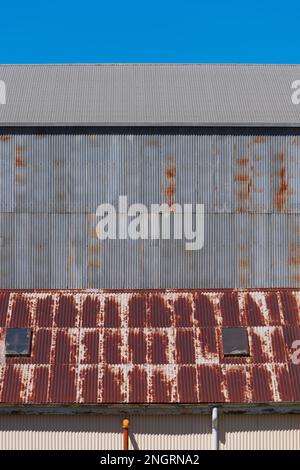 Metal corrugated iron factory wall and rusted roof with blue sky in Castlemaine Australia. Stock Photo