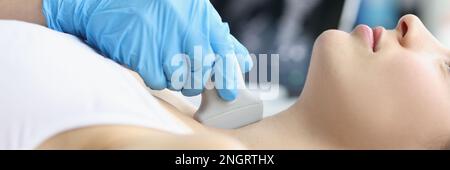 Woman receives ultrasound of thyroid gland from doctor Stock Photo