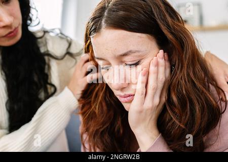 Sad young teenage girl comforted by her friend at home Stock Photo