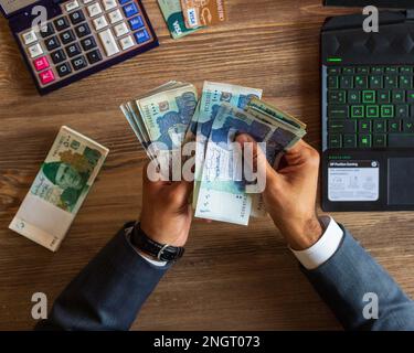 Business man hand counting Pakistani currency notes for budget Saving money investment and financial accounting management or growing business concept Stock Photo