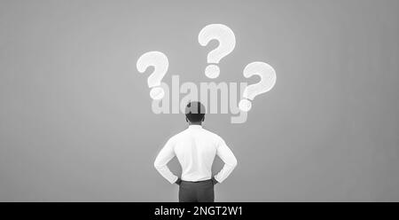 Questions, African American business man looking at questions marks, why what where when how who. person having dilemma, standing his back in grey wal Stock Photo