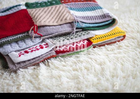 Knitted warm blanket on bed. Woolen plaid on white sofa. Patchwork plaid. Cozy room interior. Hygge style in bedroom. Knitting hobby. Winter coziness. Stock Photo