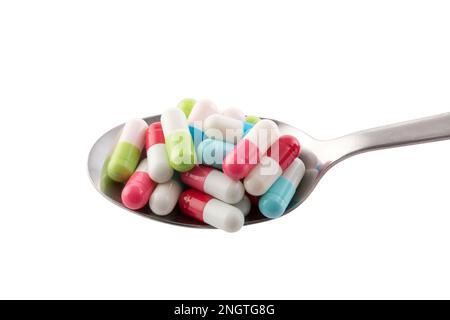 Colorful pills on spoon isolated on white background with clipping path Stock Photo