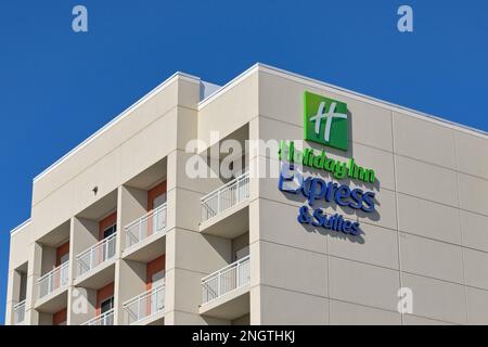 Galveston, Texas - February 2023: Sign on the outside of the Holiday Inn Express Inn and Suites hotel against a deep blue sky Stock Photo