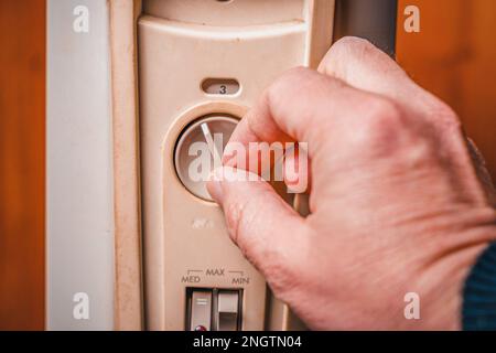 The man turns on the heater. Close-up of the hand, power buttons and temperature control Stock Photo