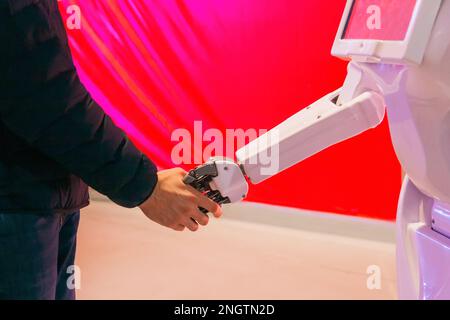 Man gives his hand to shake it to robot. The interaction of humans and artificial intelligence. Stock Photo