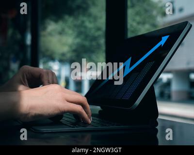 Digital investment analysis, trading, financial business growth concepts. Blue glowing arrow with grow graph on tablet computer screen using by busine Stock Photo