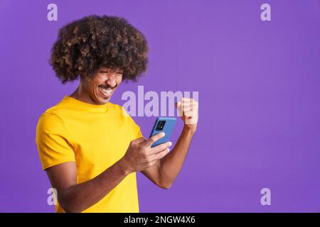Excited african man celebrating while using the mobile phone Stock Photo