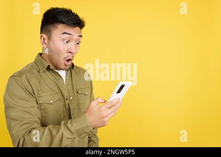 Surprised chinese man looking the screen of a mobile Stock Photo
