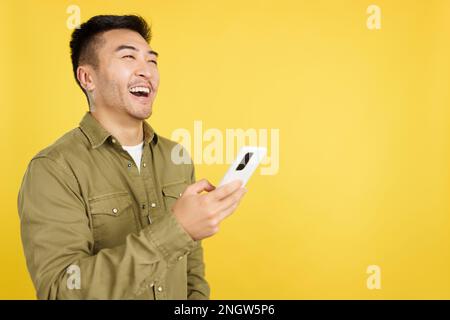 Happy chinese man laughing while using the mobile Stock Photo