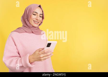 Happy muslim woman smiling while using a mobile phone Stock Photo