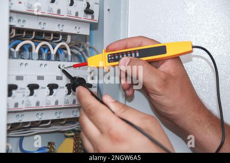 Electrician with multimeter probe at an electrical switchgear ca Stock Photo