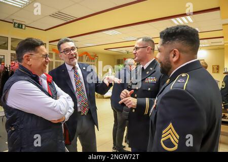 MARTIN, Slovakia - Jan Kriska, left, a member of Rotary International Club Martin, and Ivan Lamos, President of Rotary Club International Martin, left center, speak with U.S. Army V Corps Capt. Robert Pavlovic, right center, and Staff Sgt. Zachery Garcia, right, both Civil Affairs Soldiers assigned to 418th Civil Affairs Battalion based out of Belton, Missouri, during Rotary International Club Martin’s Thanksgiving dinner, Martin, Slovakia, Nov. 24, 2022. Local community leaders representing the Rotary International Club invited U.S. Army V Corps Civil Affairs Soldiers from Camp Kosciuszko, Po Stock Photo