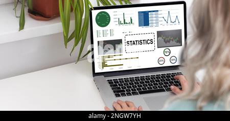 Laptop Computer Showing Statistical Infographics Stands on a Desk in the Living Room. In the Background Cozy Living Room. Stock Photo