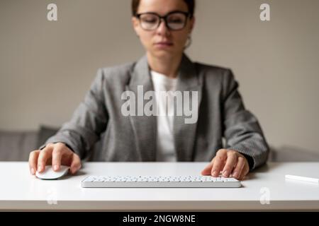 Businesswoman working on pc with blank virtual monitor using wireless keyboard and computer mouse, space for photomontage insert infographic. Stock Photo