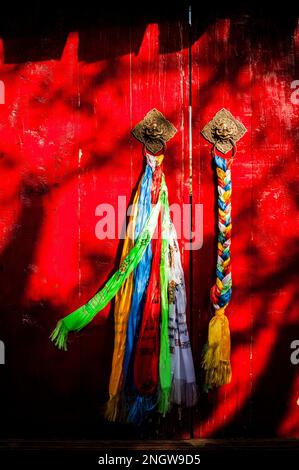 chinese prayer flags hanging on red door Stock Photo
