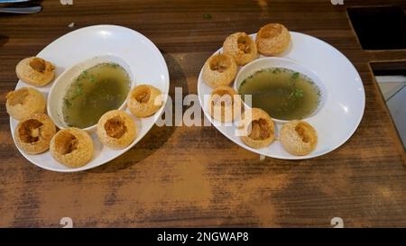 Two plates of Pani Puri or Golgappa or Puchkas from a white plate which is popular Indian Chat menu. Stock Photo