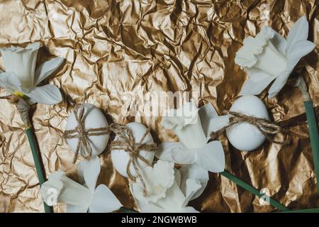 White Easter eggs with flowers on golden background, close up. Concept of Easter Sunday,  religious traditions and symbolism Stock Photo