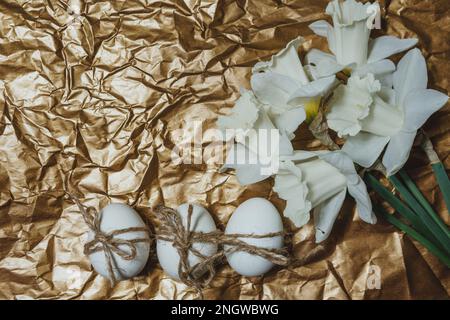White Easter eggs with flowers on golden background, close up. Concept of Easter Sunday,  religious traditions and symbolism Stock Photo