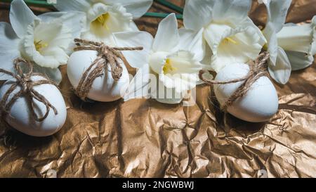 White Easter eggs with flowers on golden background, close up. Concept of Easter Sunday,  religious traditions and symbolism Stock Photo