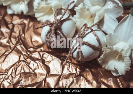 White Easter eggs with flowers on golden background, close up. Concept of Easter Sunday,  religious traditions and symbolism Stock Photo