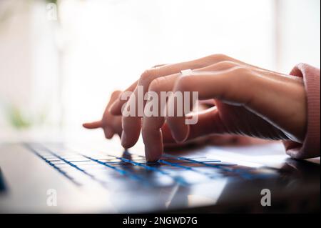 Low angle closeup view of female hands typing on laptop computer keyboard. Stock Photo