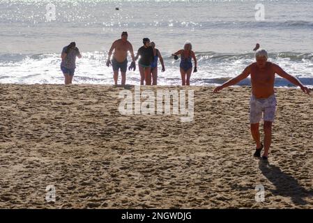 Boscombe, Bournemouth, Dorset, UK, 19th February 2023, Weather. Cold water swimmers emerge from the sea on sunny Sunday as temperatures rise to 14 degrees in the south of England in warm late winter sunshine. Credit: Paul Biggins/Alamy Live News Stock Photo