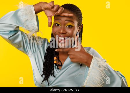 Pretty Black Lady Framing Face With Fingers Over Yellow Background Stock Photo