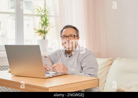 Cheerful senior man has phone conversation at home Stock Photo