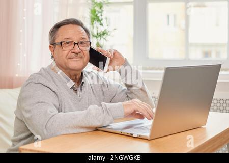 Cheerful senior man has phone conversation at home Stock Photo