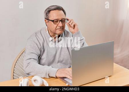 Senior man at home connected on laptop computer Stock Photo