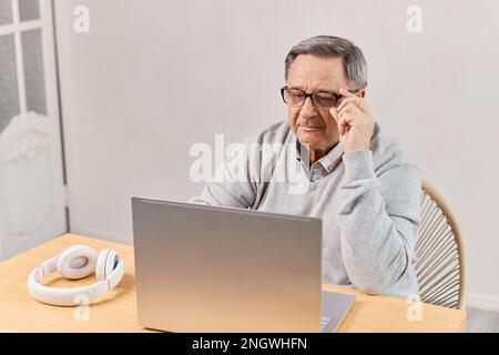 Senior man at home connected on laptop computer Stock Photo