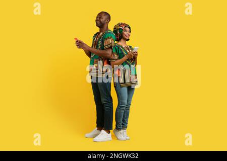 Beautiful loving black couple in traditional costumes using cell phones Stock Photo