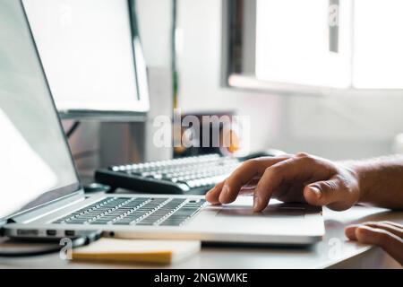 Person using the touchpad of a modern laptop. Unrecognizable young man working at his desk with computers. Freelance man working, student doing homewo Stock Photo