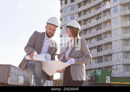 two architects holding blueprint discussing project while working together Stock Photo
