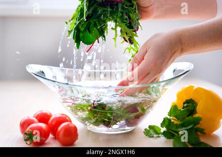 Super Slow Motion Shot of Flying Cuts of Colorful Vegetables and Water Drops Woman washing in water in sink green kale cabbage leaves in kitchen, organic healthy food. High quality 4k footage Stock Photo