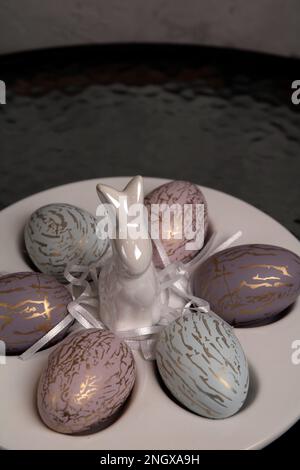 photo decorative eggs in a special plate for eggs and white rabbit figurine stands on the table Stock Photo