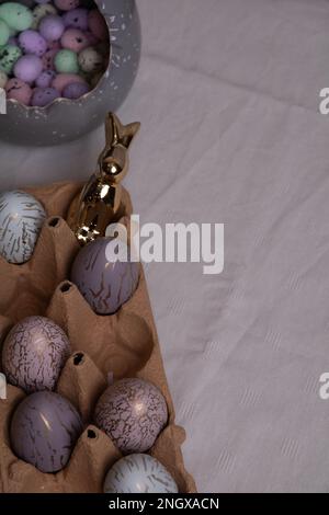 photo multicolored chicken eggs lying in a tray and a decorative rabbit on the table Stock Photo