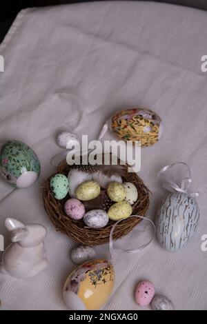 photo in a bird's nest for quail eggs, next to a rabbit and decorative chicken eggs on the table Stock Photo