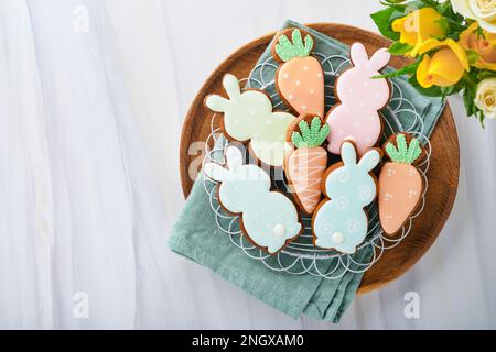 Easter breakfast Holliday concept. Easter gingerbread shape of bunny and carrot with cinnamon with colored glaze, easter decorations, colored eggs on Stock Photo