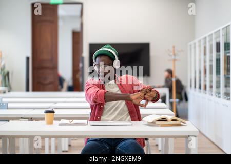 Tired student yawns and stretch arms in lecture class after sleepless night preparing for exam test. Stock Photo