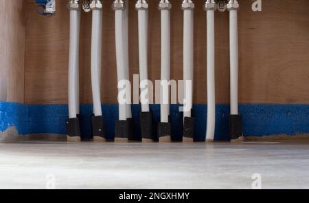 Close-up view of underfloor heating system manifold with multiple plastic pipes and thermal insulation on floor Stock Photo