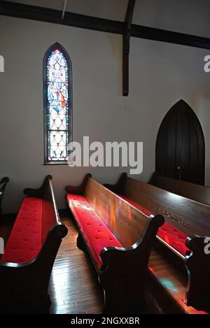 Sunlight streams through stain glass windows onto pews at the Holy Trinity Episcopal Church, completed in 1850 in rural Hertford, North Carolina. Stock Photo