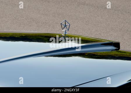 The Pentastar hood ornament and hood on a dark blue 1982 Chrysler New Yorker Fifth Avenue Edition in bright sun. Stock Photo
