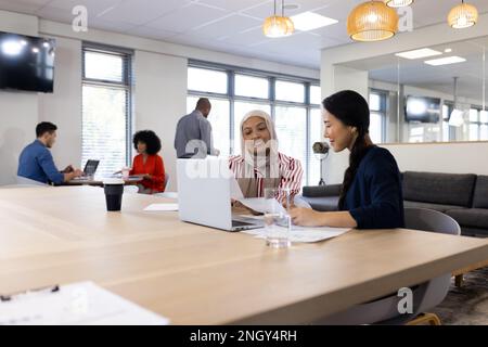 Image of diverse female colleagues working on laptop in office Stock Photo